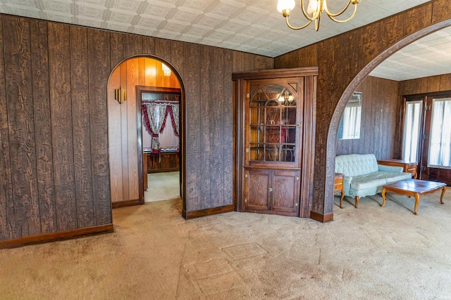 interior space featuring wood walls, light colored carpet, and a notable chandelier