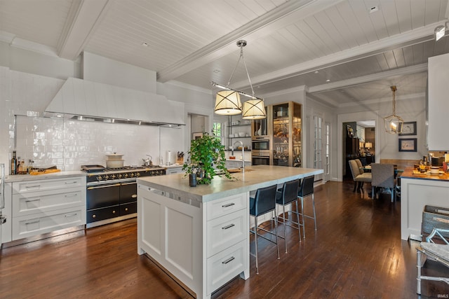 kitchen featuring pendant lighting, a kitchen island with sink, beamed ceiling, dark hardwood / wood-style floors, and white cabinetry