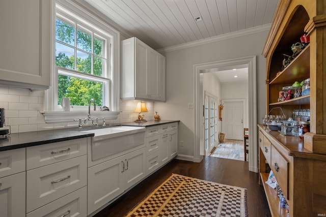 kitchen featuring white cabinetry, sink, ornamental molding, dark hardwood / wood-style floors, and decorative backsplash