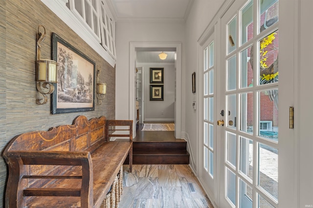 hall with ornamental molding, a healthy amount of sunlight, and light hardwood / wood-style flooring