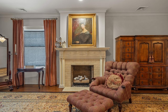 living area with hardwood / wood-style floors, ornamental molding, and a fireplace