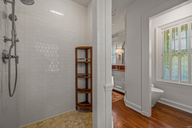 bathroom featuring hardwood / wood-style flooring, vanity, toilet, and a tile shower