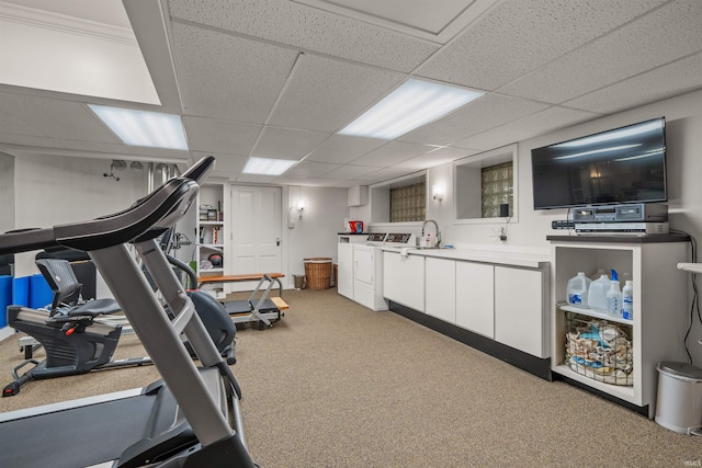 exercise room with a drop ceiling, light colored carpet, and washing machine and clothes dryer