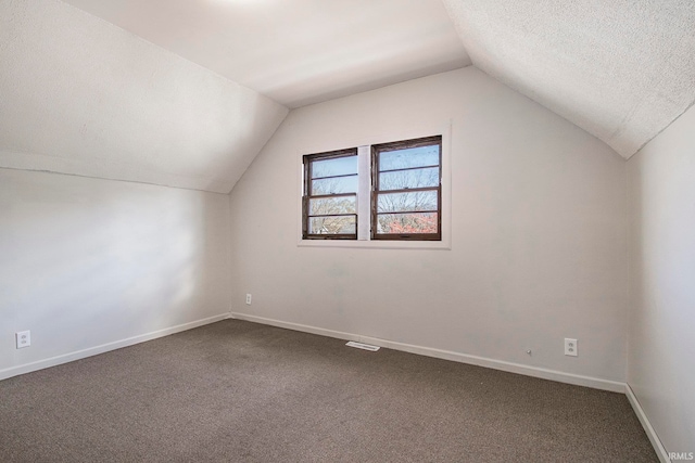 additional living space with a textured ceiling, carpet floors, and vaulted ceiling