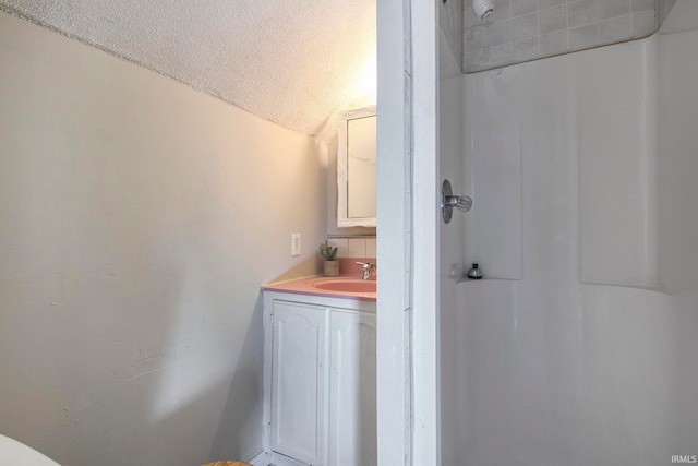 bathroom with vanity, lofted ceiling, and a textured ceiling