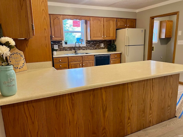 kitchen featuring dishwasher, sink, white refrigerator, backsplash, and kitchen peninsula