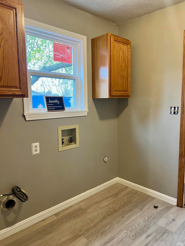 washroom with cabinets, light hardwood / wood-style floors, a textured ceiling, and washer hookup