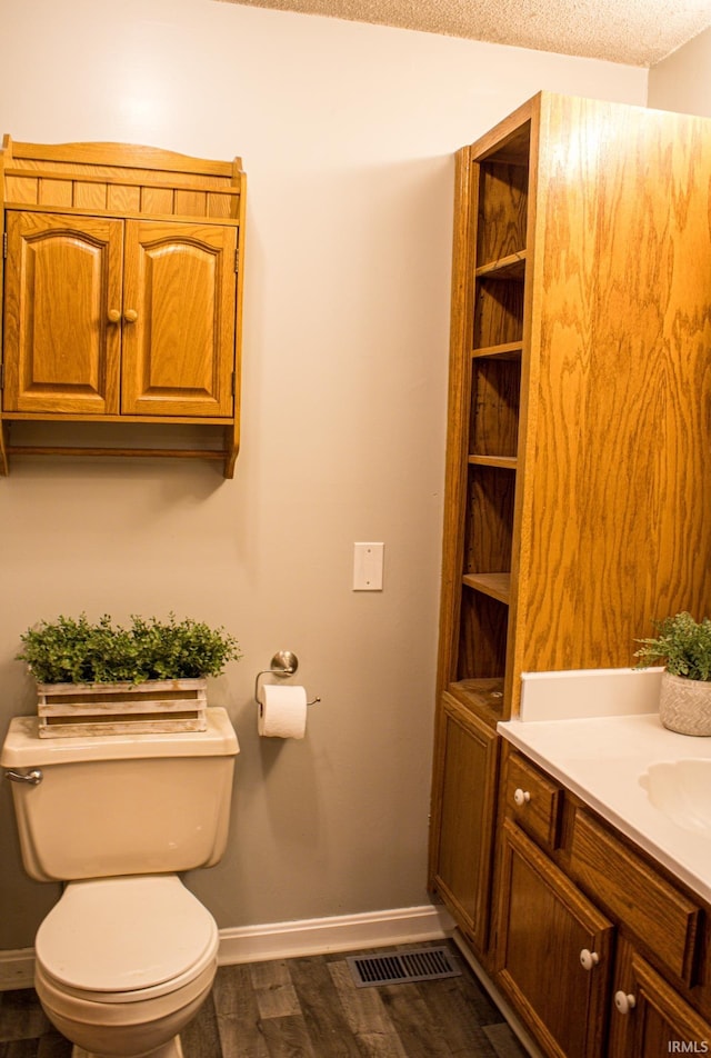 bathroom featuring hardwood / wood-style floors, vanity, toilet, and a textured ceiling