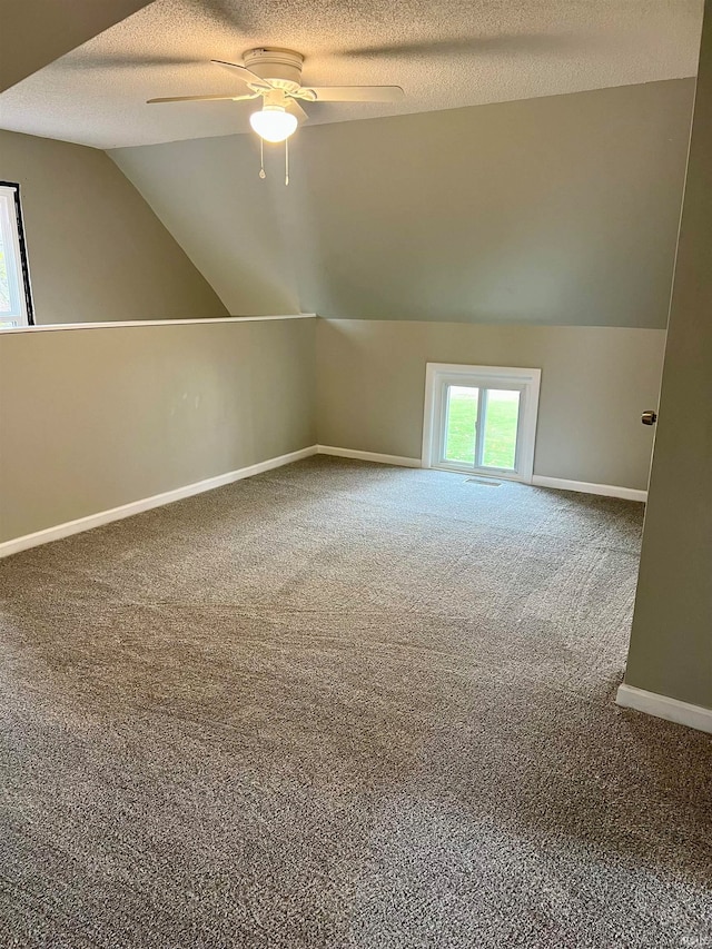 bonus room with lofted ceiling, carpet, a textured ceiling, and ceiling fan