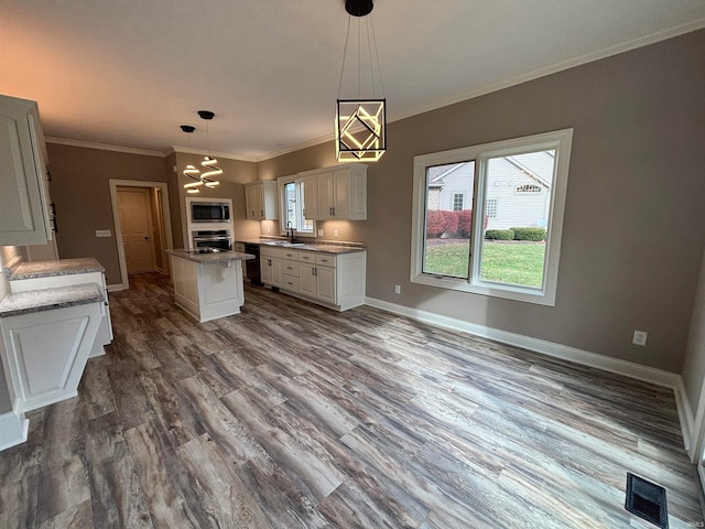 kitchen with wood-type flooring, white cabinets, sink, pendant lighting, and appliances with stainless steel finishes