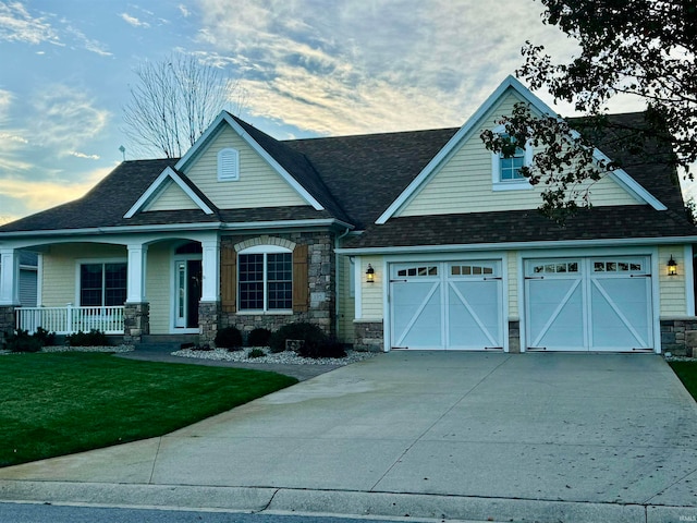 craftsman-style home featuring a front lawn, a porch, and a garage