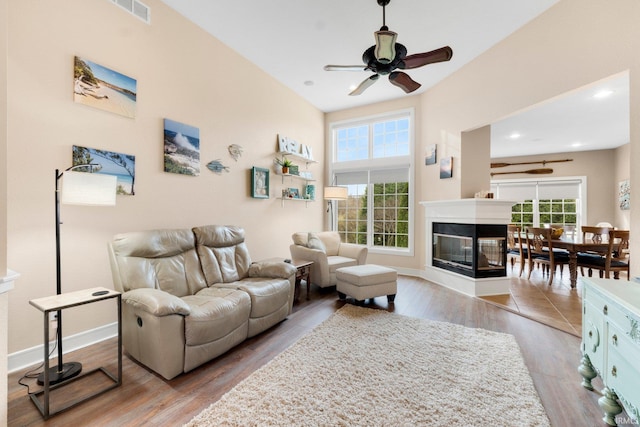 living room featuring a multi sided fireplace, light wood-type flooring, and a wealth of natural light