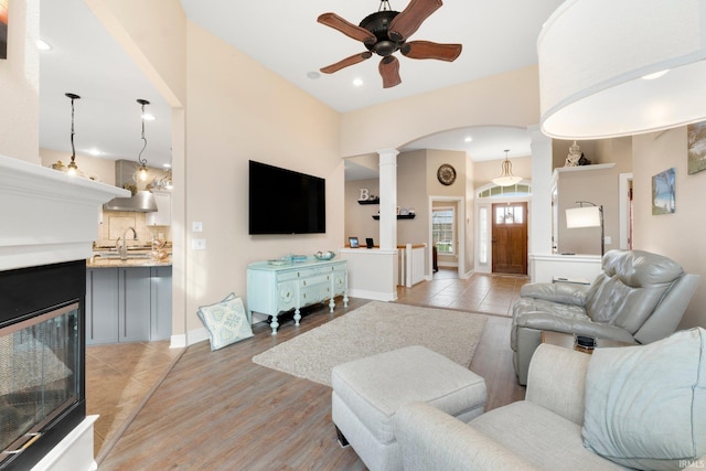 living room featuring ornate columns, ceiling fan, light hardwood / wood-style flooring, and sink