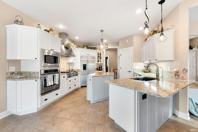 kitchen featuring a center island, wall chimney range hood, kitchen peninsula, pendant lighting, and appliances with stainless steel finishes