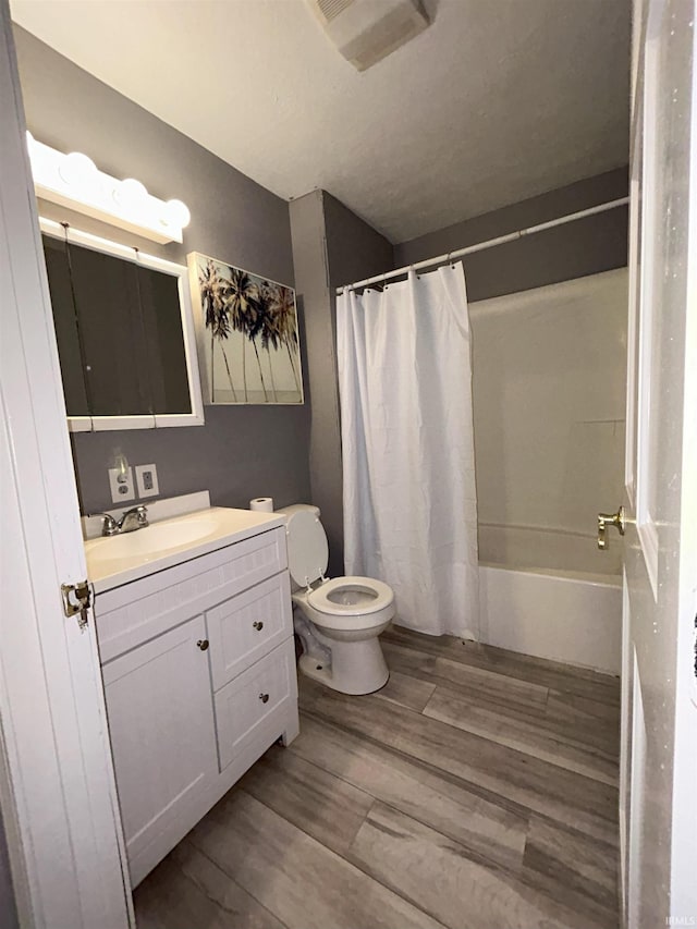 full bathroom with hardwood / wood-style floors, shower / tub combo with curtain, vanity, and toilet