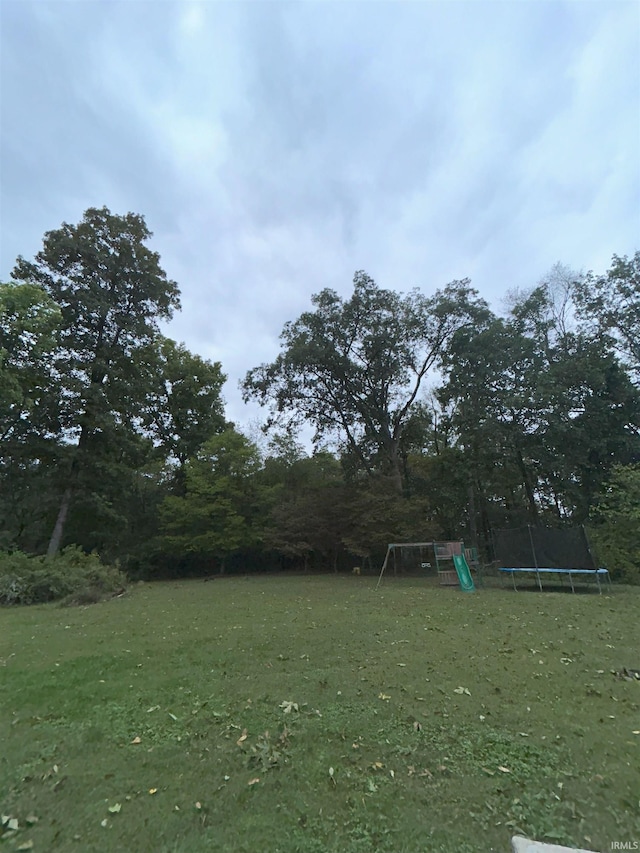 view of yard featuring a playground and a trampoline