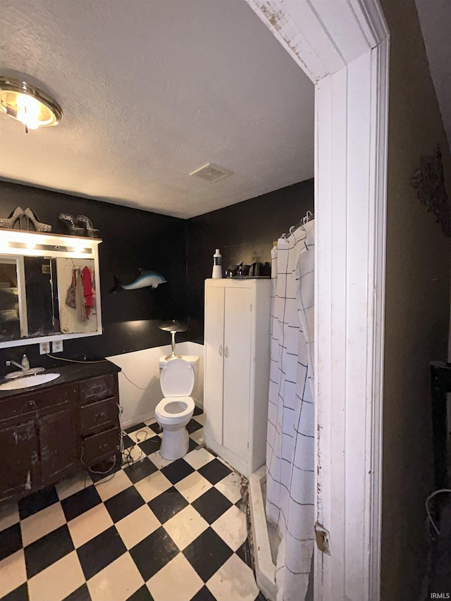 bathroom with curtained shower, vanity, a textured ceiling, and toilet