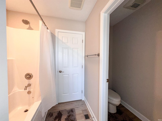 bathroom featuring hardwood / wood-style floors, toilet, and shower / tub combo with curtain