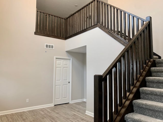 staircase featuring a high ceiling and hardwood / wood-style floors