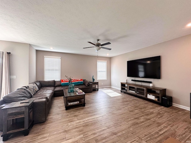 living room featuring light wood-type flooring, a textured ceiling, and ceiling fan