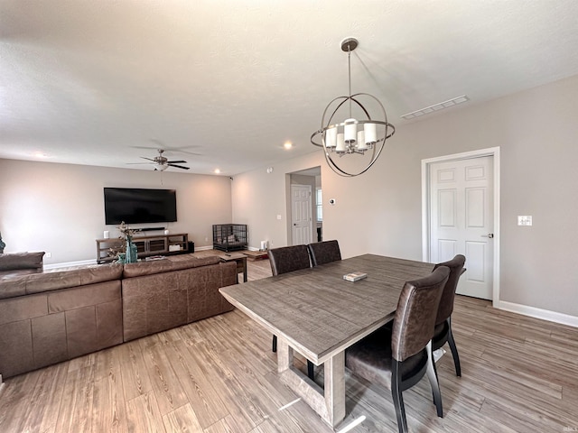 dining space featuring ceiling fan with notable chandelier and light hardwood / wood-style flooring