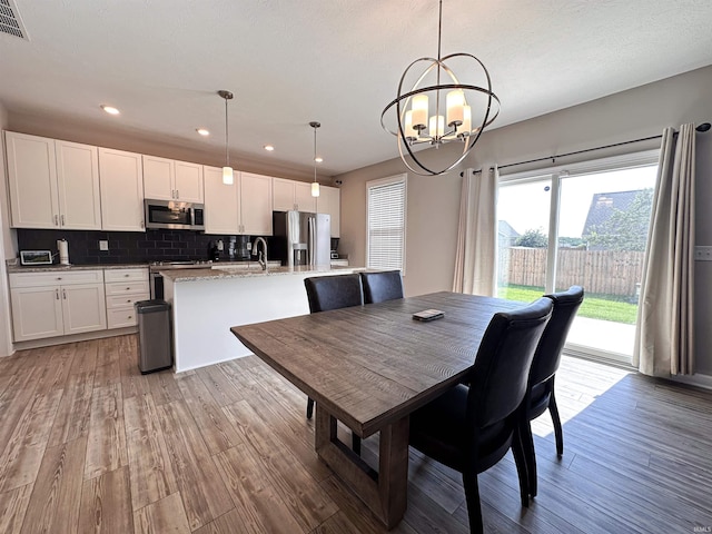 dining area featuring light wood-type flooring and an inviting chandelier