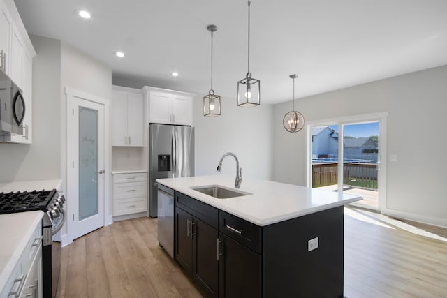 kitchen with light hardwood / wood-style floors, sink, a kitchen island with sink, white cabinetry, and appliances with stainless steel finishes