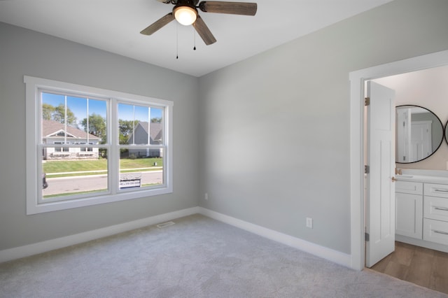 unfurnished bedroom with ceiling fan, connected bathroom, and light carpet