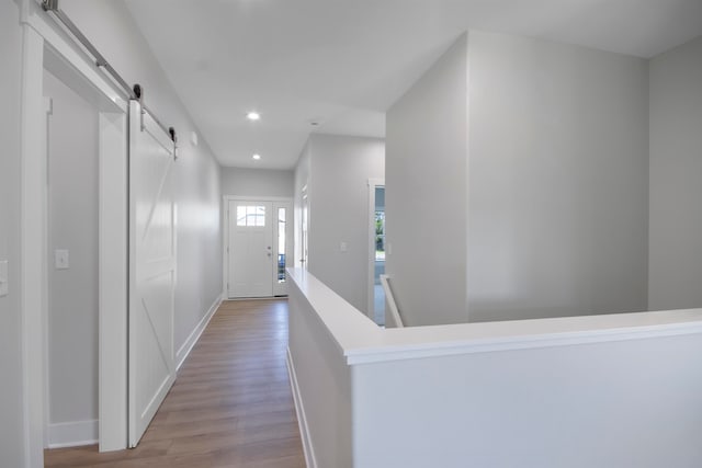 corridor with light wood-type flooring and a barn door