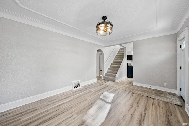 unfurnished living room featuring light hardwood / wood-style floors, a textured ceiling, and ornamental molding