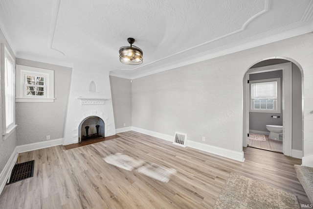 unfurnished living room featuring a fireplace, light hardwood / wood-style floors, and ornamental molding