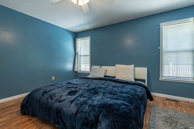 bedroom featuring multiple windows, hardwood / wood-style floors, and ceiling fan