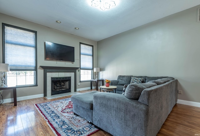 living room with wood-type flooring, a healthy amount of sunlight, a textured ceiling, and a tiled fireplace