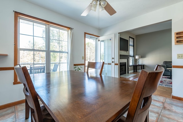 tiled dining area featuring a tiled fireplace and ceiling fan