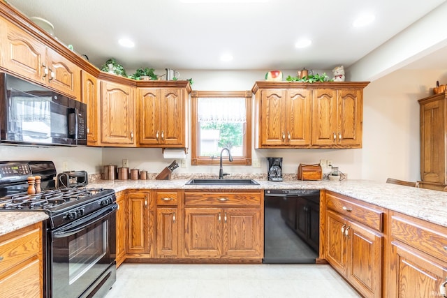 kitchen featuring black appliances, sink, and light stone countertops