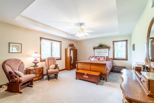 bedroom with a tray ceiling, light carpet, and ceiling fan