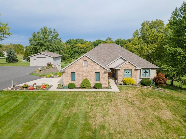 view of front of home with a garage, a front yard, and an outdoor structure