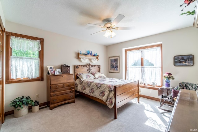 carpeted bedroom with a textured ceiling, multiple windows, and ceiling fan