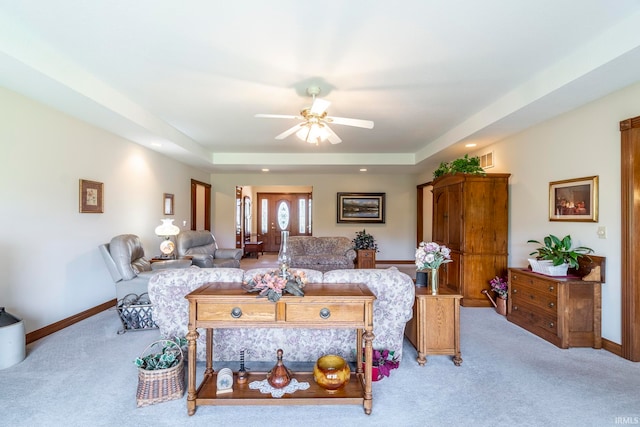 living room featuring light carpet, ceiling fan, and a tray ceiling