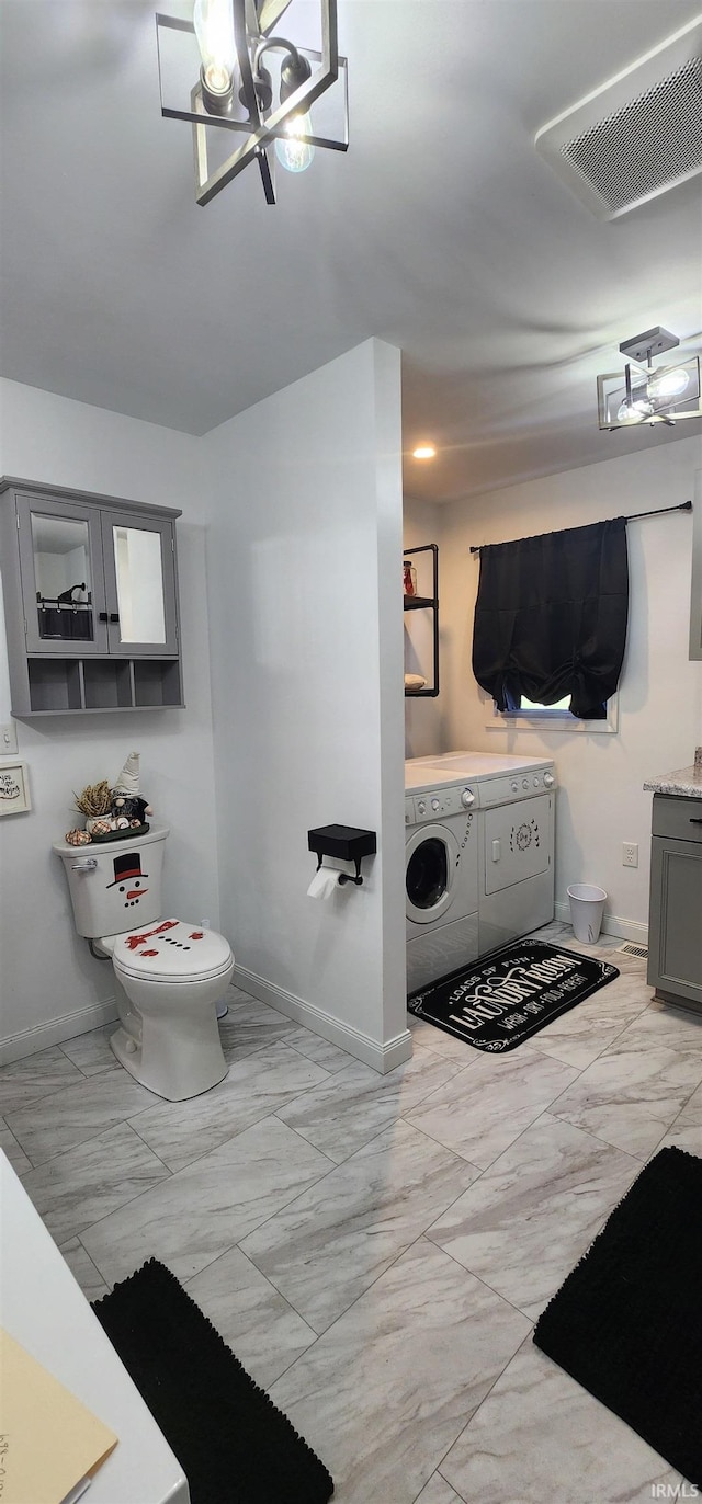 bathroom featuring toilet, vanity, independent washer and dryer, and a notable chandelier