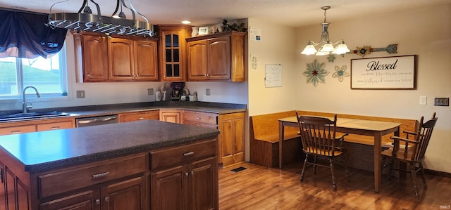 kitchen with an inviting chandelier, sink, stainless steel dishwasher, light wood-type flooring, and decorative light fixtures