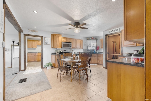 dining space with light tile patterned flooring, ceiling fan, and a textured ceiling