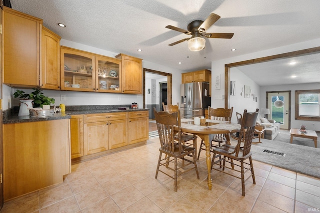 dining room with a textured ceiling, vaulted ceiling, and light tile patterned flooring