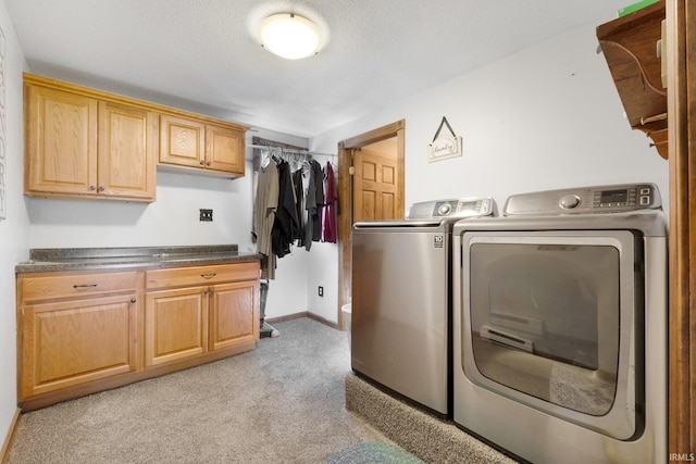 laundry room featuring cabinets, separate washer and dryer, a textured ceiling, and light colored carpet