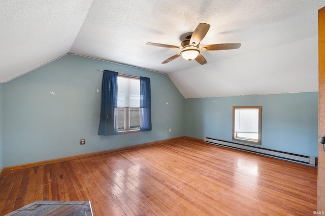 bonus room featuring lofted ceiling, hardwood / wood-style floors, a healthy amount of sunlight, and a baseboard heating unit