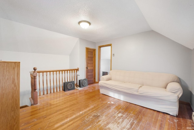 interior space with a textured ceiling, hardwood / wood-style flooring, and vaulted ceiling