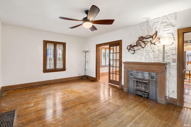 unfurnished living room featuring french doors, hardwood / wood-style flooring, ceiling fan, and a fireplace