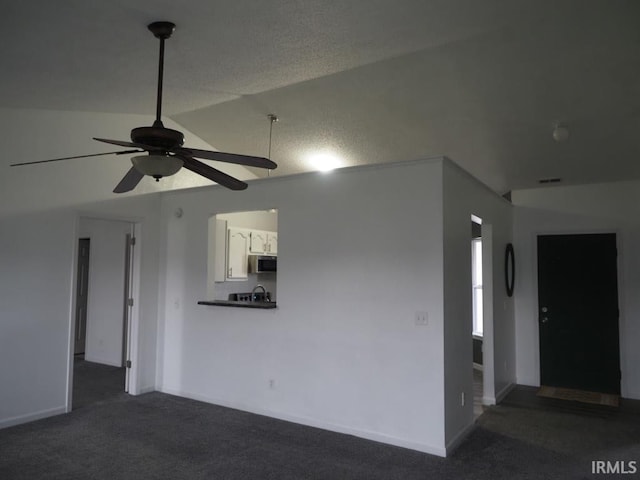 empty room with sink, ceiling fan, vaulted ceiling, and dark carpet