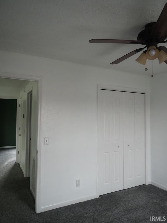 unfurnished bedroom with ceiling fan, dark colored carpet, and a closet