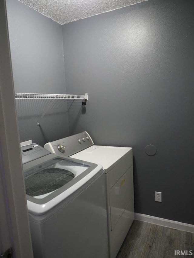 washroom featuring dark wood-type flooring, a textured ceiling, and washer and clothes dryer